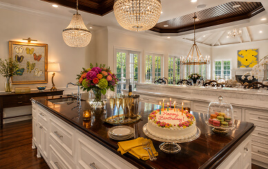 Kitchen island set for a birthday celebration with flowers, cake, and champagne
