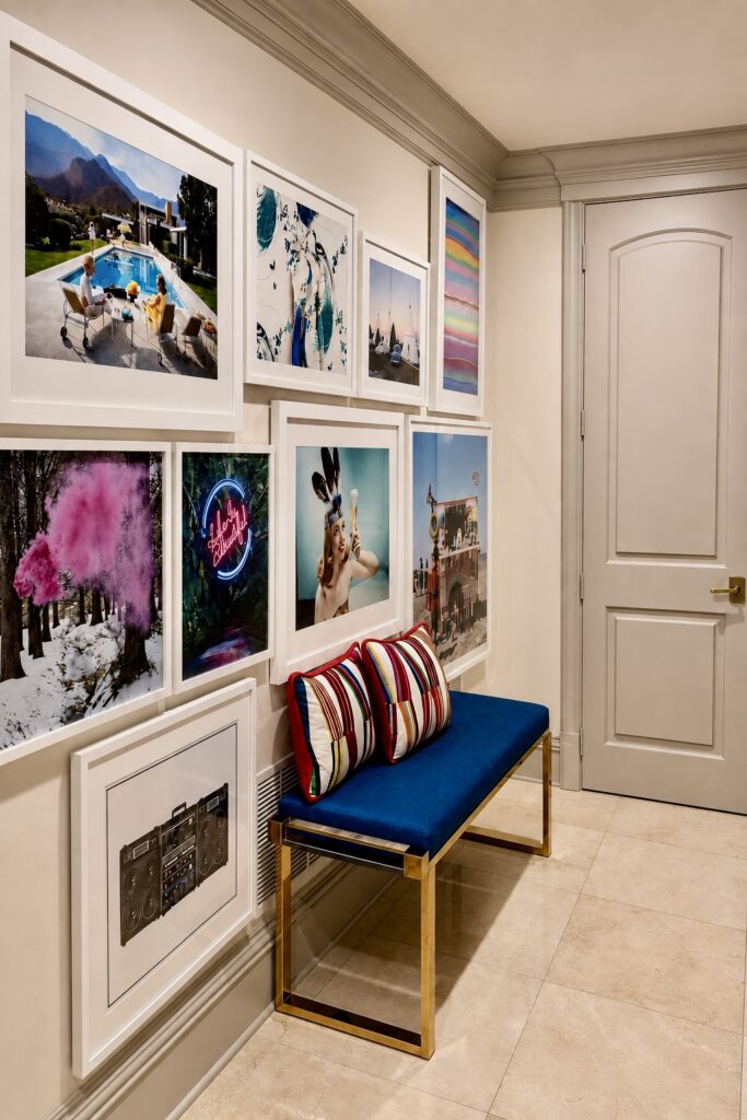 Hallway gallery wall of framed photography above a navy bench