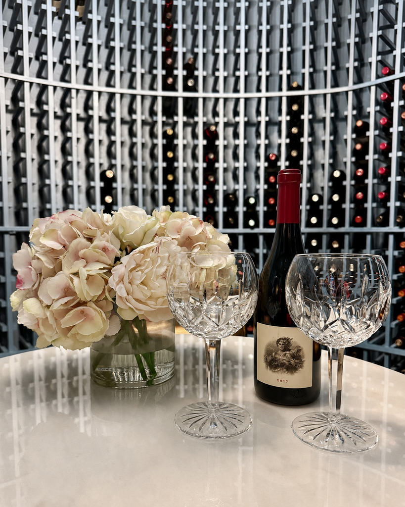 Wine bottle and crystal glasses on a marble table in a wine cellar