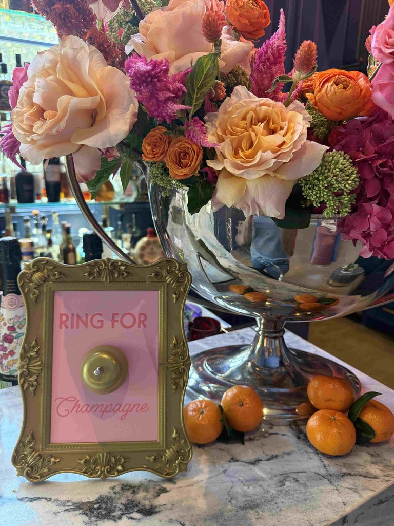 Floral arrangement beside a gold 'Ring for Champagne' button