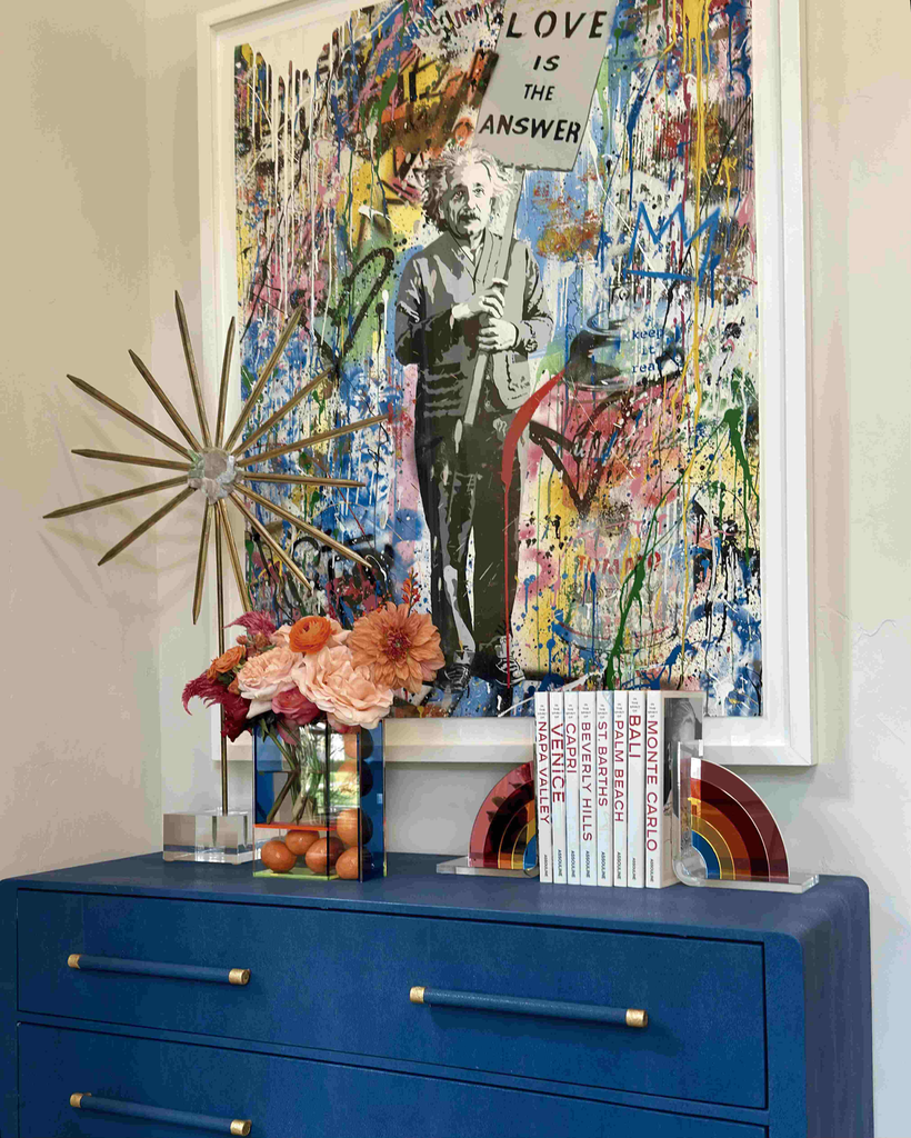 Blue chest styled with flowers and books beneath large graffiti-style artwork