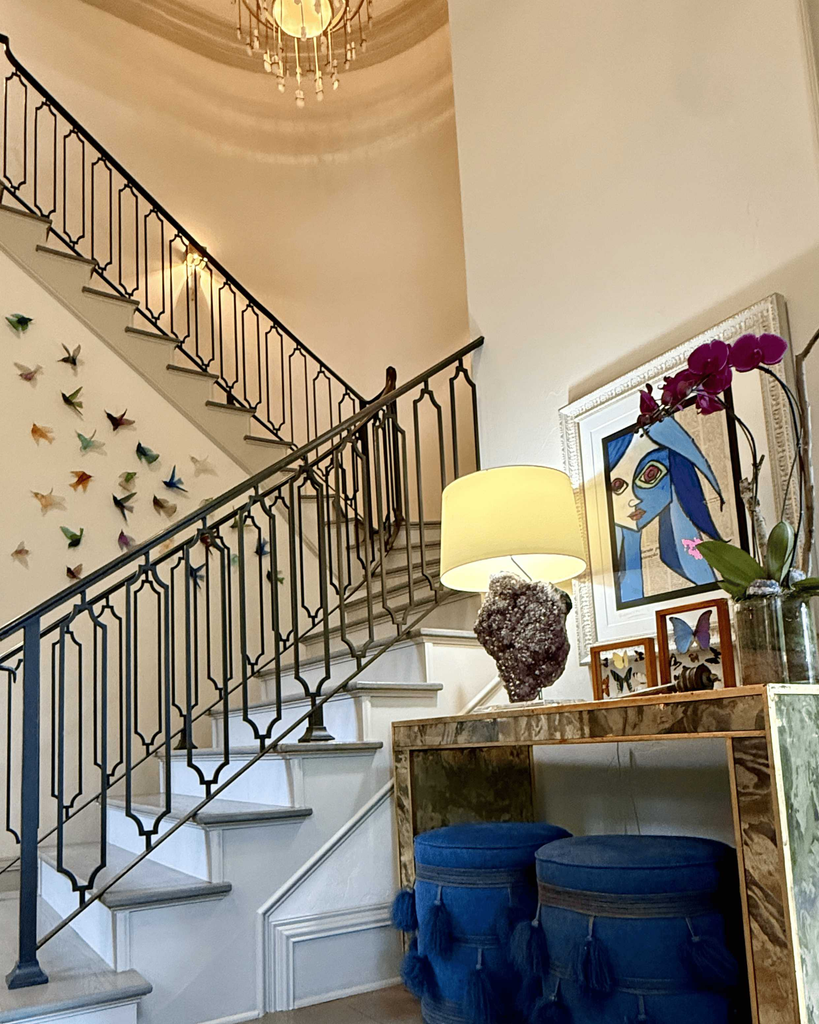 Foyer staircase with an iron railing, butterfly wall art, and a marble console