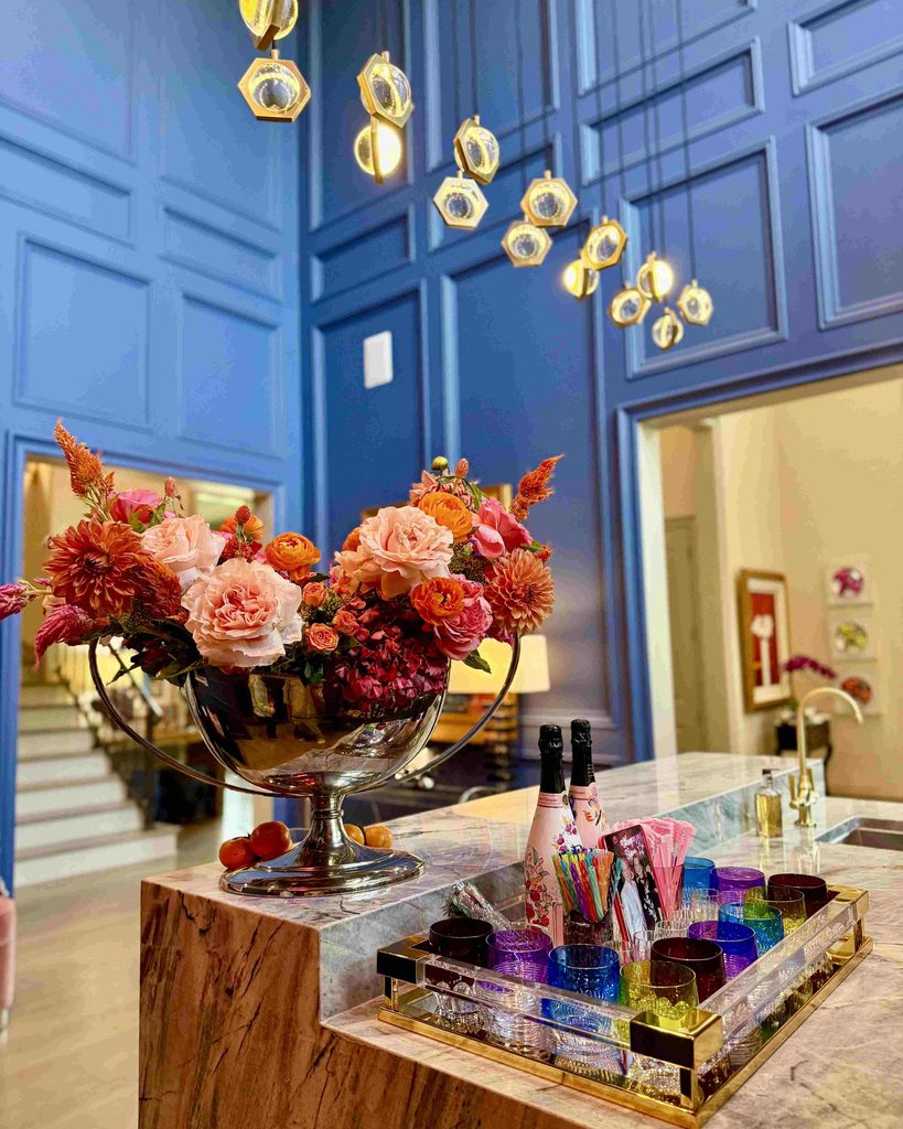 Blue paneled bar with a floral arrangement and a colorful glassware tray