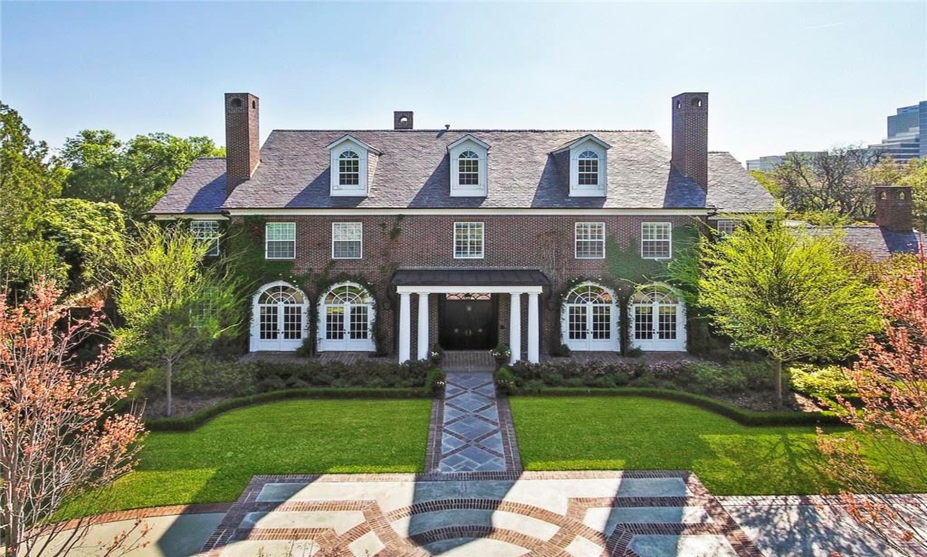 Brick colonial home with arched windows and a patterned stone front walk