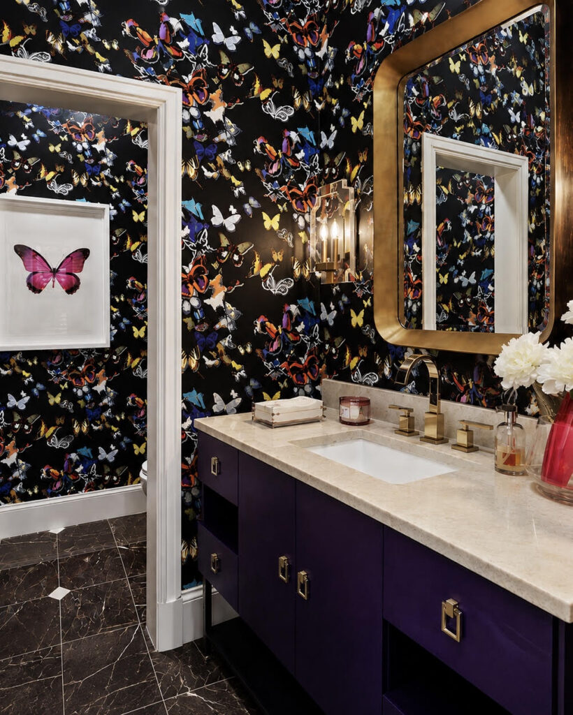 Powder room with butterfly wallpaper, a gold mirror, and a purple vanity