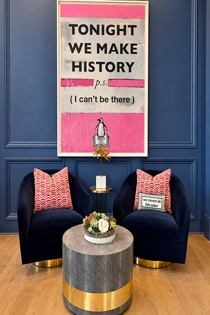 Navy paneled sitting nook with velvet swivel chairs and a pink 'Tonight We Make History' print