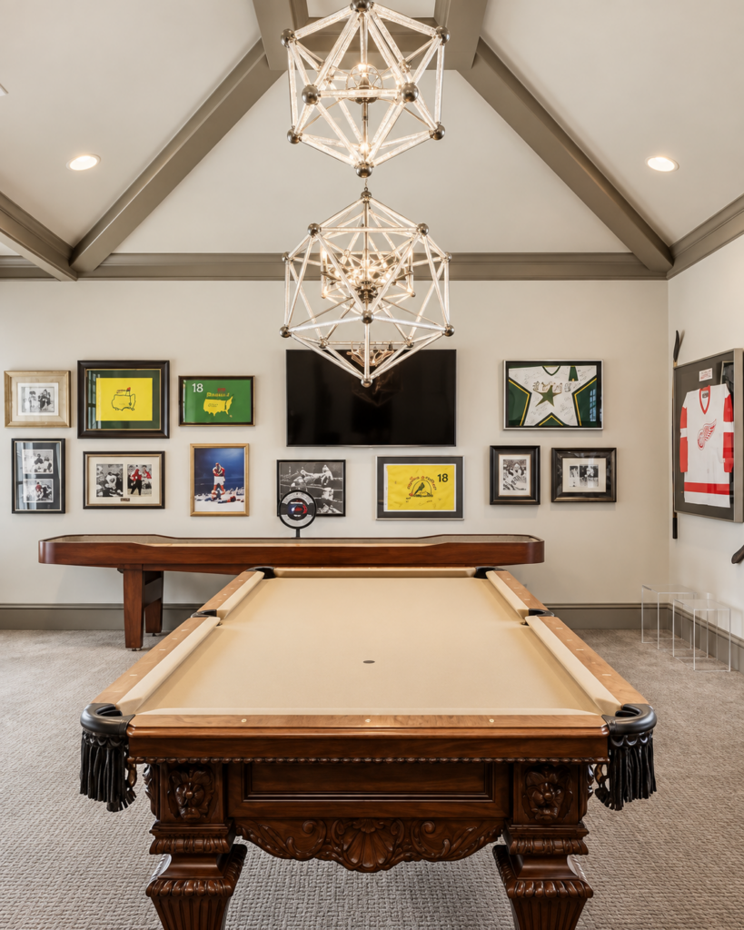 Game room with a pool table, geometric chandeliers, and framed sports memorabilia